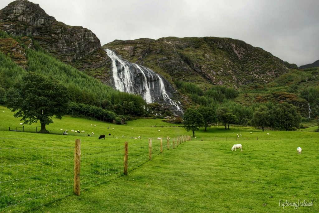 The field before the waterfall in Gleninchaquin Park, Co. Kerry, dotted with sheep - Hikes In Ireland